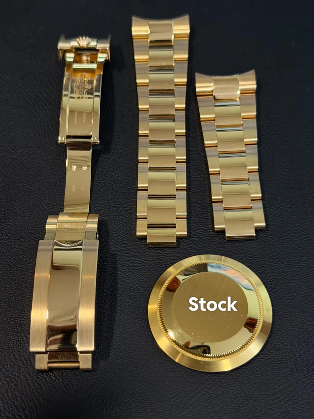 Finished yellow gold bracelet, clasp, and caseback set next to stock finish reference
