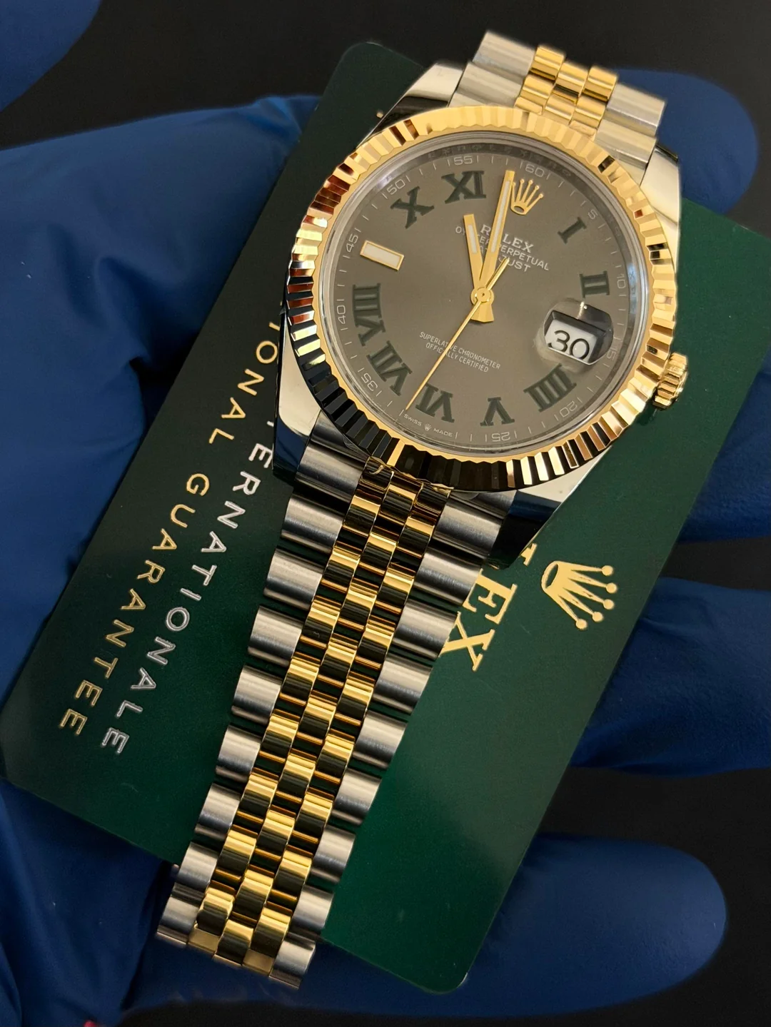 Two-tone yellow gold jubilee bracelet watch with fluted bezel and grey dial, on the International Guarantee card