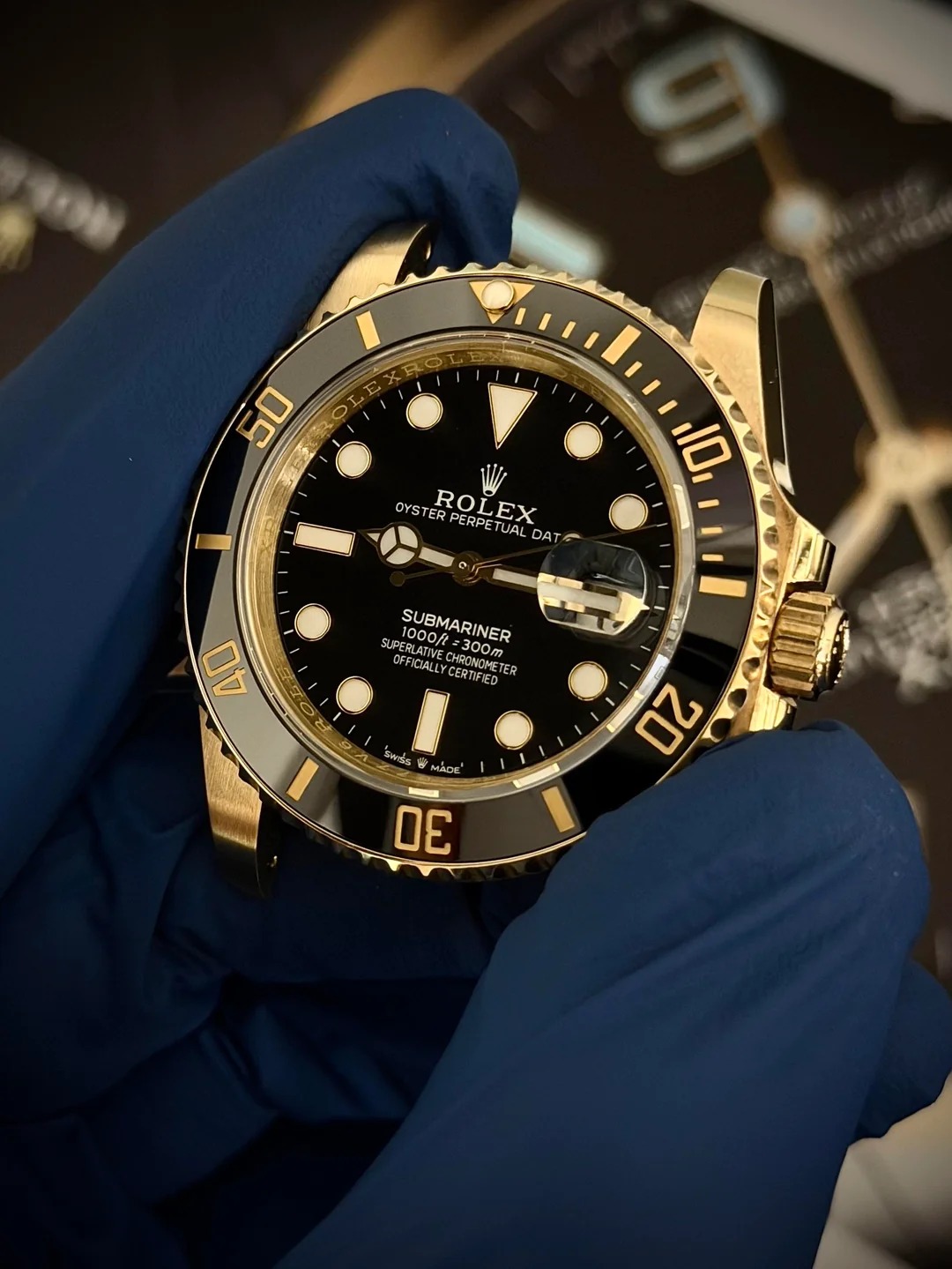 Yellow gold Submariner with black dial, held in hand